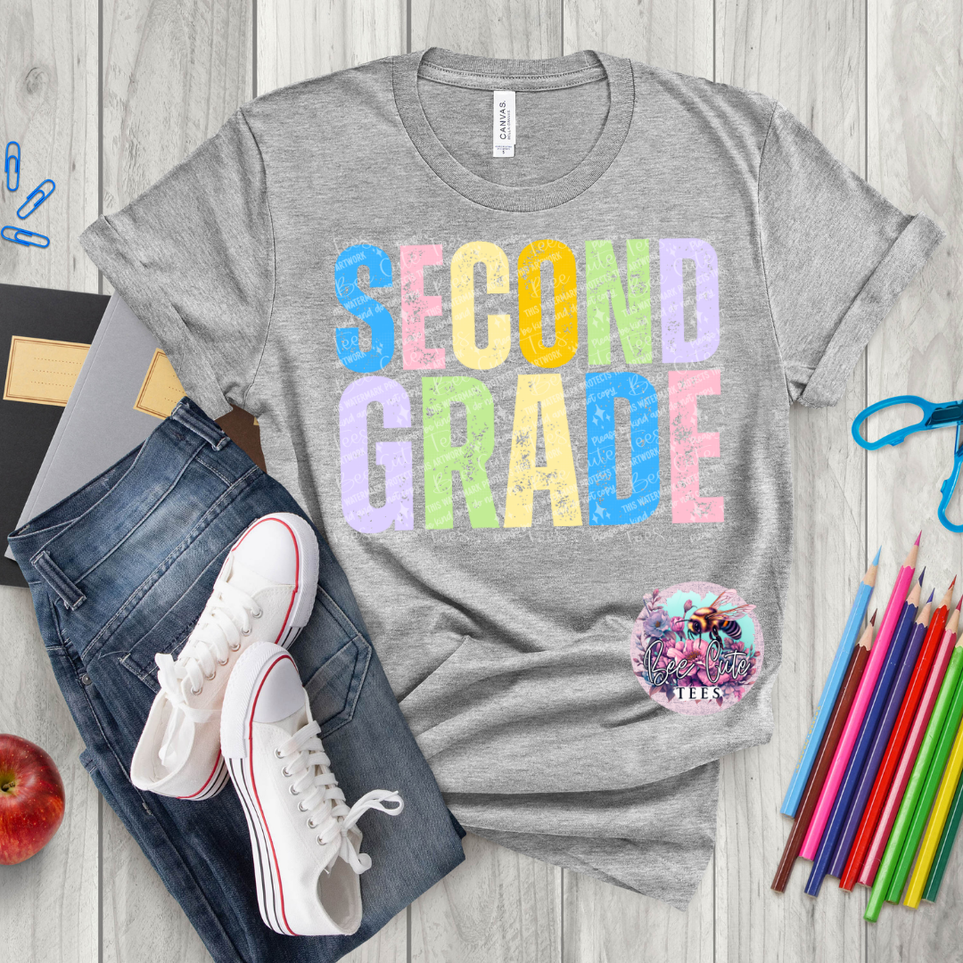 Gray t-shirt with 'SECOND GRADE' text, jeans, sneakers, and school supplies on a wooden surface