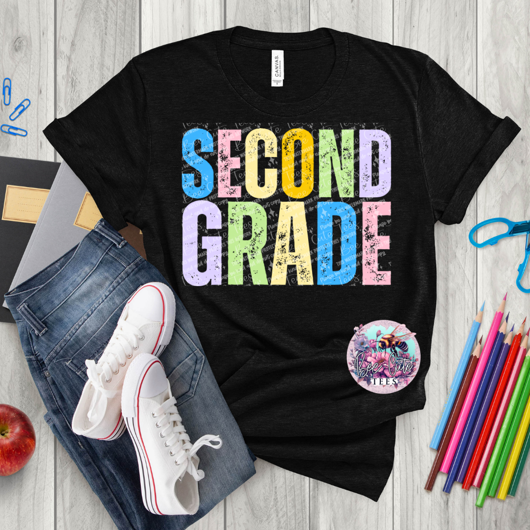 Black t-shirt with 'SECOND GRADE' in colorful letters on a wooden surface with jeans, sneakers, and school supplies.
