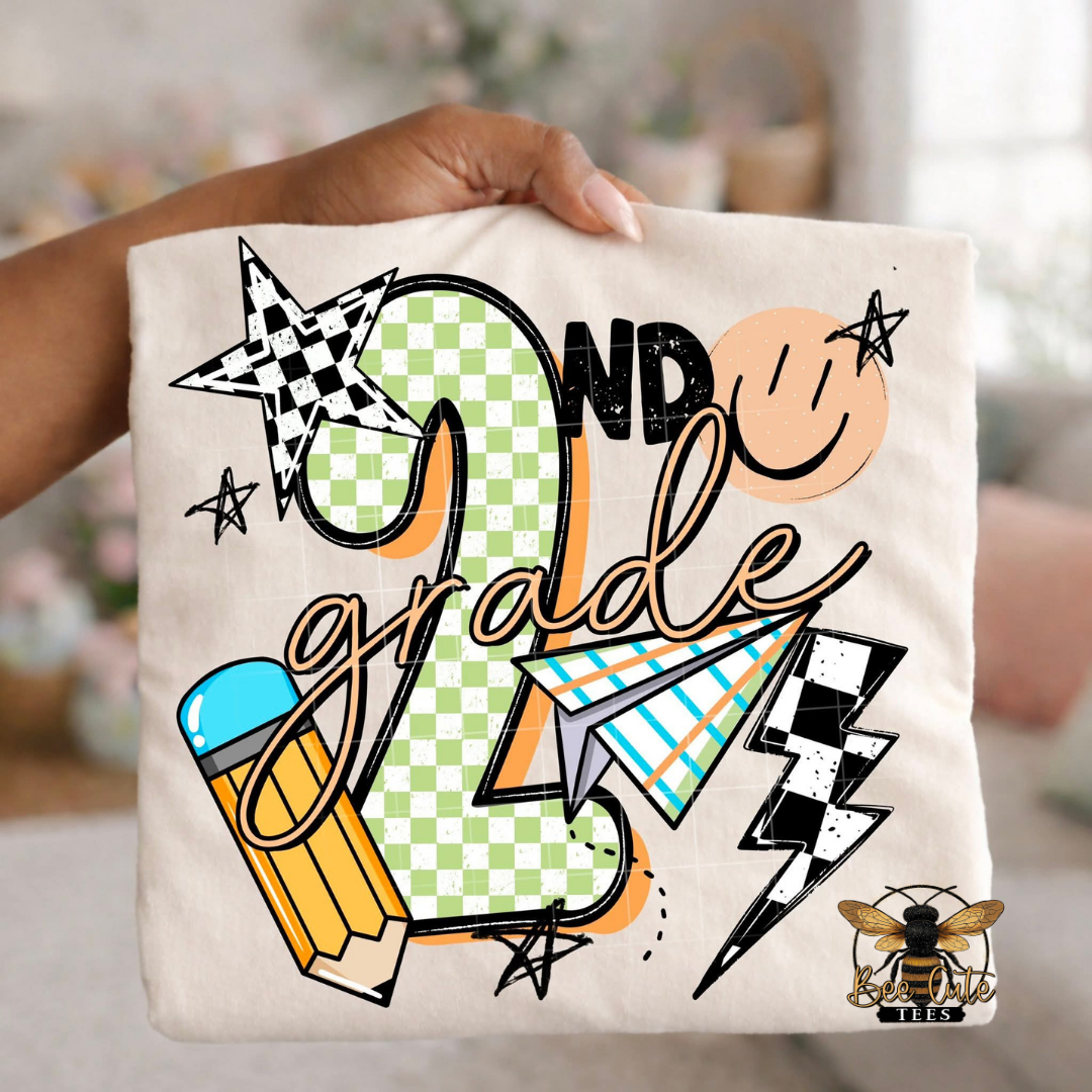 Folded white-colored unisex T-shirt held up by a hand, featuring a colorful "2nd Grade" graphic. The design includes green checkered number four, bold black lettering, peach script, a pencil, paper airplane, smiley face, lightning bolt, stars, and playful doodles. A fun, retro-inspired back-to-school design perfect for fourth grade teachers and students.
