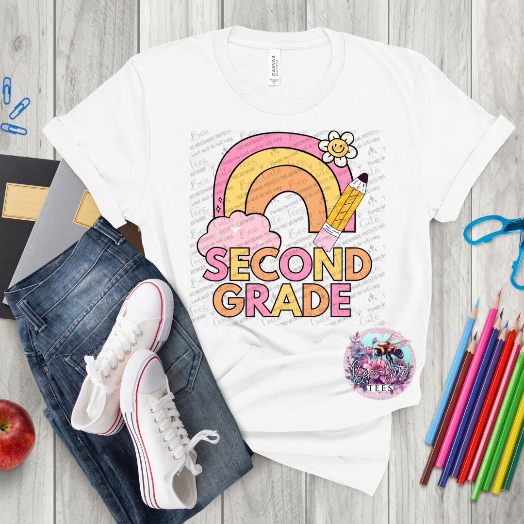 White t-shirt with 'Second Grade' design on a wooden surface with jeans, sneakers, and school supplies.