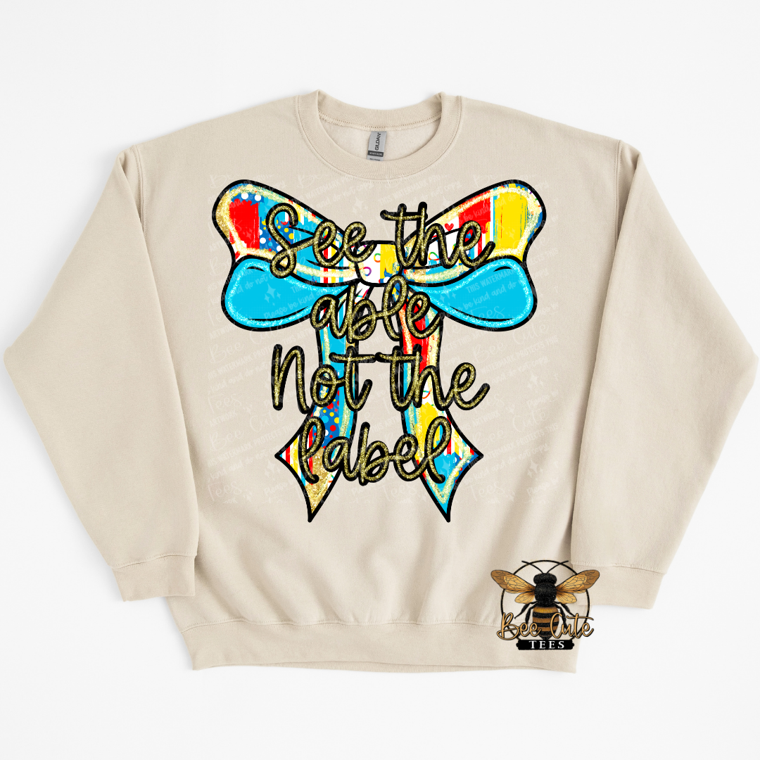 Beige sweatshirt with a colorful bow graphic and text on a white background