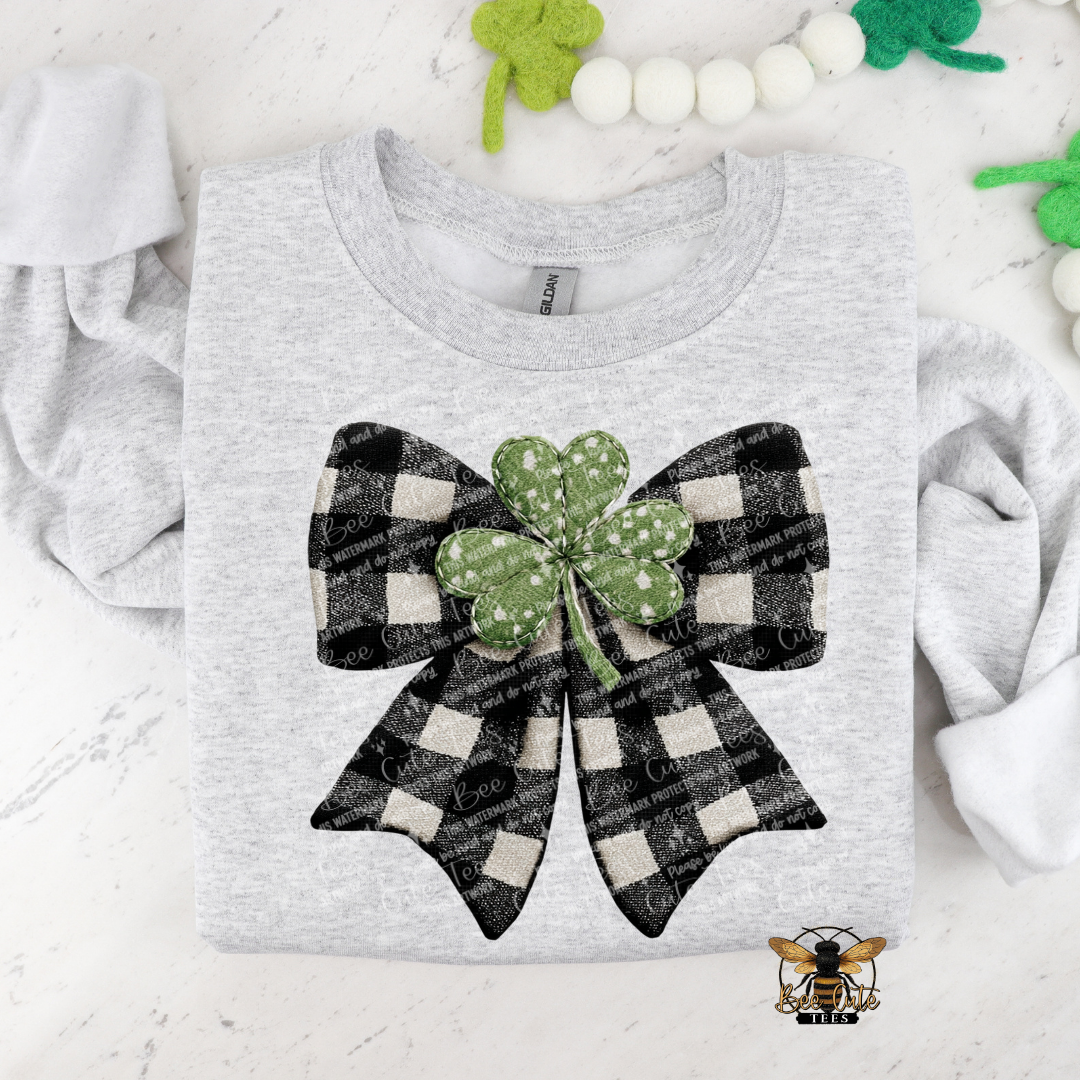 Gray t-shirt with a black and white checkered bow and green shamrock on a white background