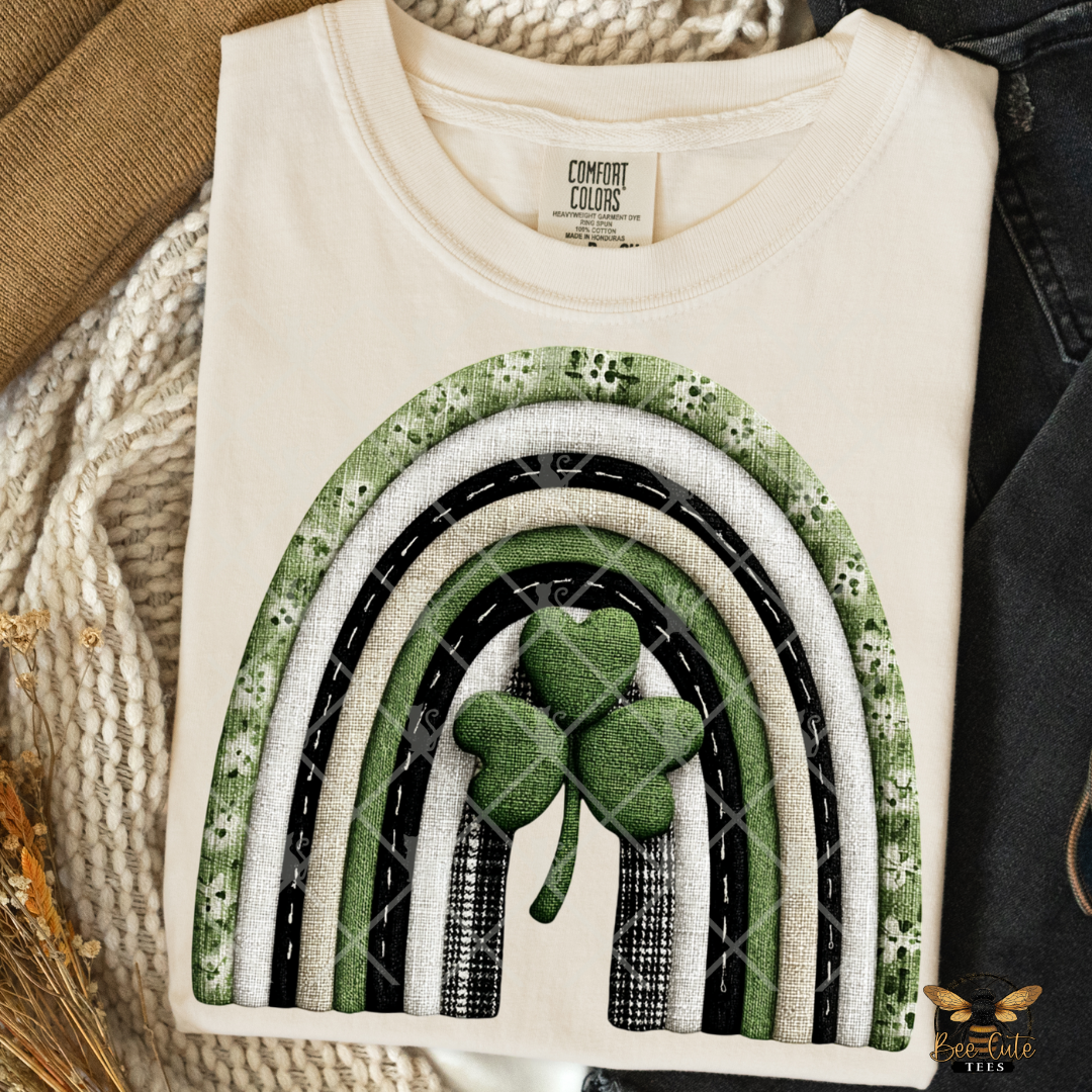 White t-shirt with rainbow and shamrock design on a textured surface
