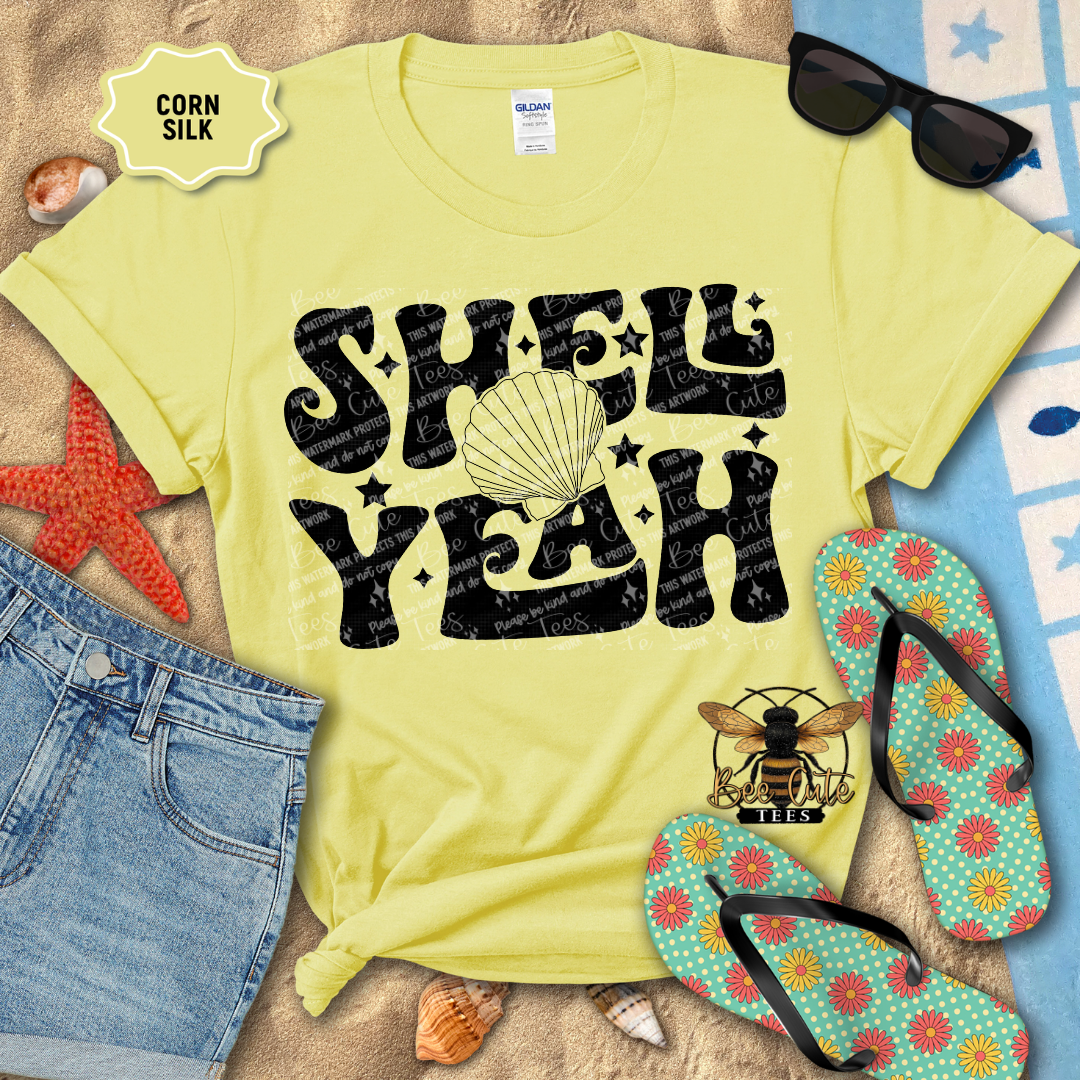 Yellow t-shirt with 'Shell Yeah' design on a beach setting with sunglasses, flip-flops, and starfish.