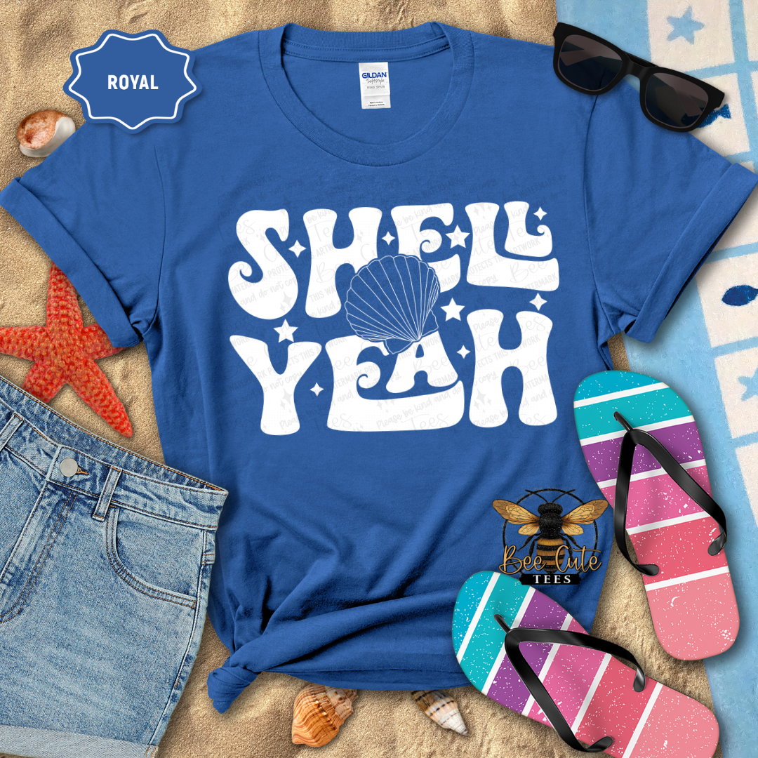 Blue t-shirt with 'Shell Yeah' design on a beach-themed background with sunglasses, flip-flops, and a starfish.
