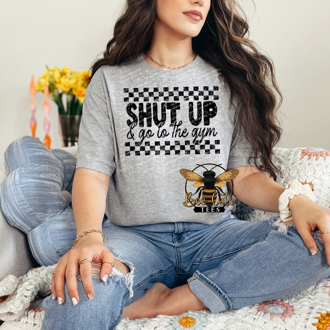 Person wearing a gray t-shirt with a bee logo and text, sitting on a couch.