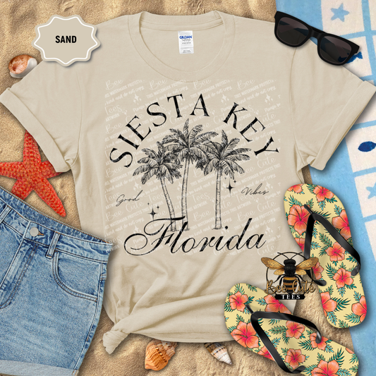 Beige t-shirt with 'Siesta Key Florida' design on a sandy background with beach accessories.