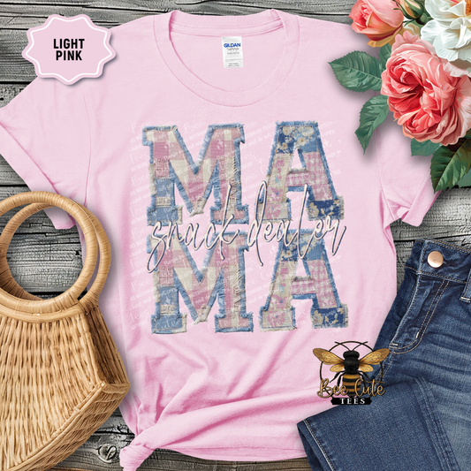 Pink t-shirt with 'MAMA' design on a wooden surface with flowers and denim jeans.