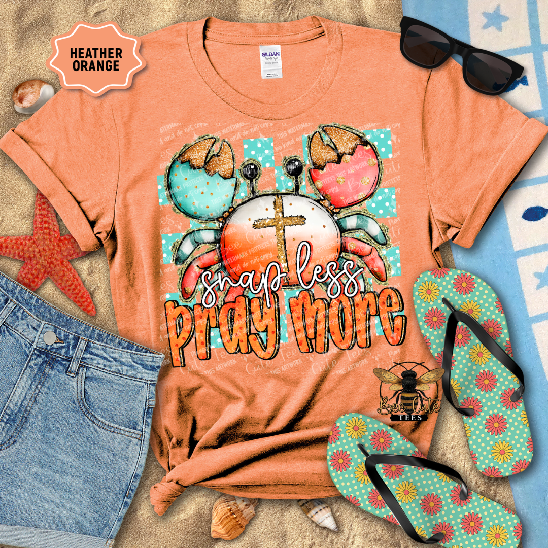 Orange t-shirt with beach-themed design and accessories on a textured surface