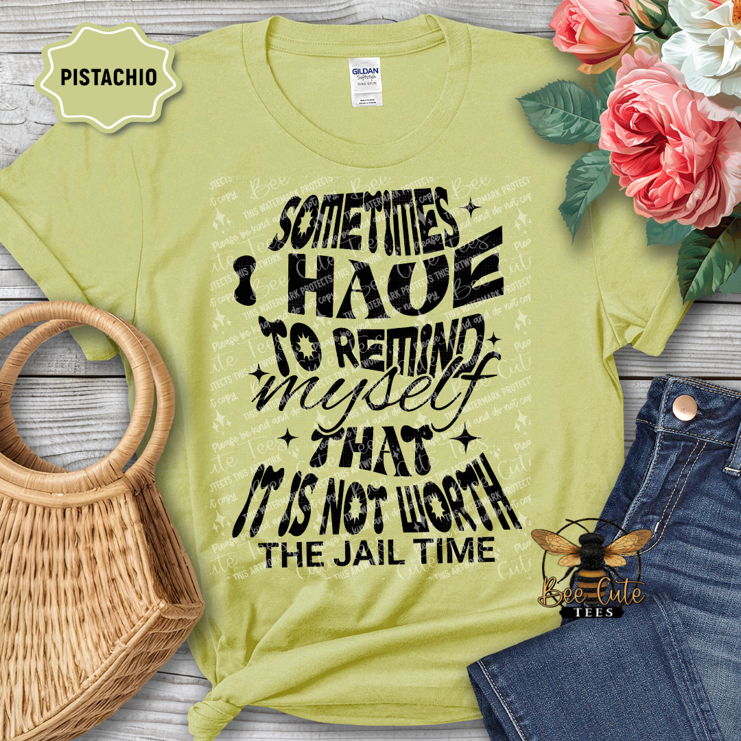 Pistachio green t-shirt with humorous text design, placed on a wooden surface with flowers and denim jeans.