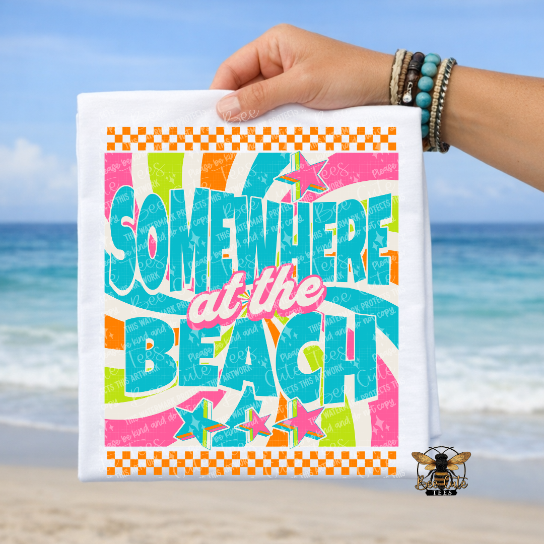 Colorful t-shirt with 'Somewhere at the Beach' text held by a hand on a beach background