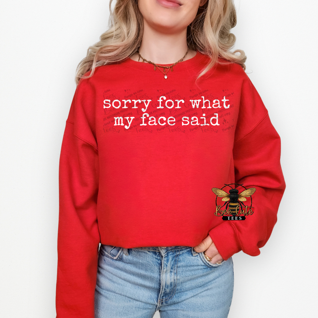 Person wearing a red sweatshirt with text 'sorry for what my face said' on a white background