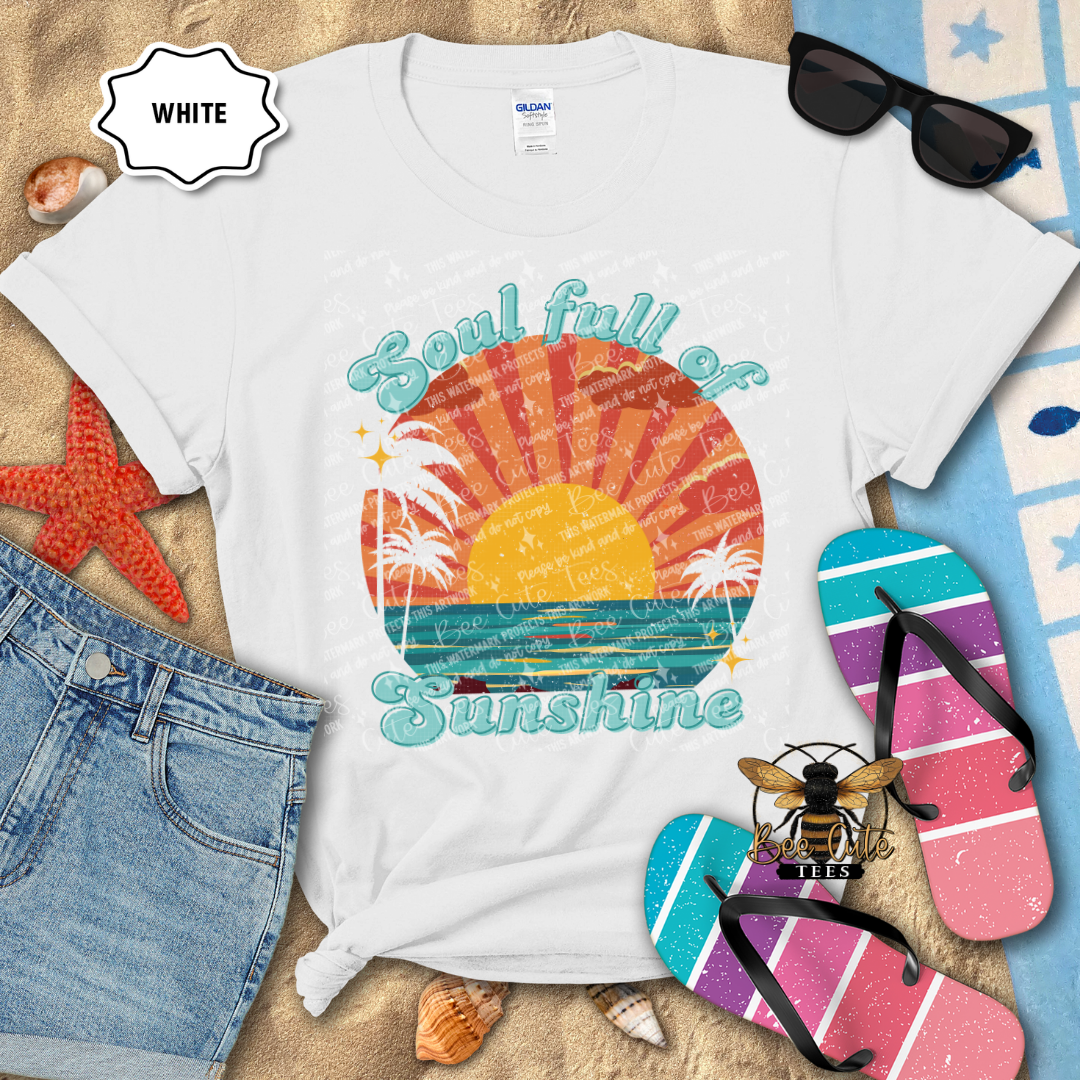White t-shirt with beach-themed design and text 'Soul full of Sunshine' on a sandy background with flip-flops and sunglasses.