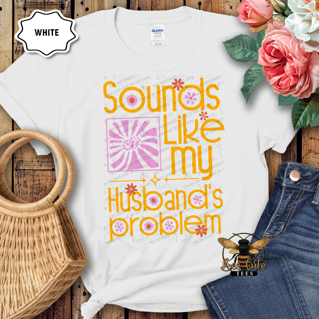 White t-shirt with colorful text design on a wooden surface with flowers and denim jeans.