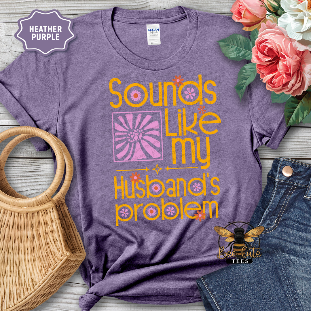 Purple t-shirt with humorous text design, placed on a wooden surface with flowers and jeans.