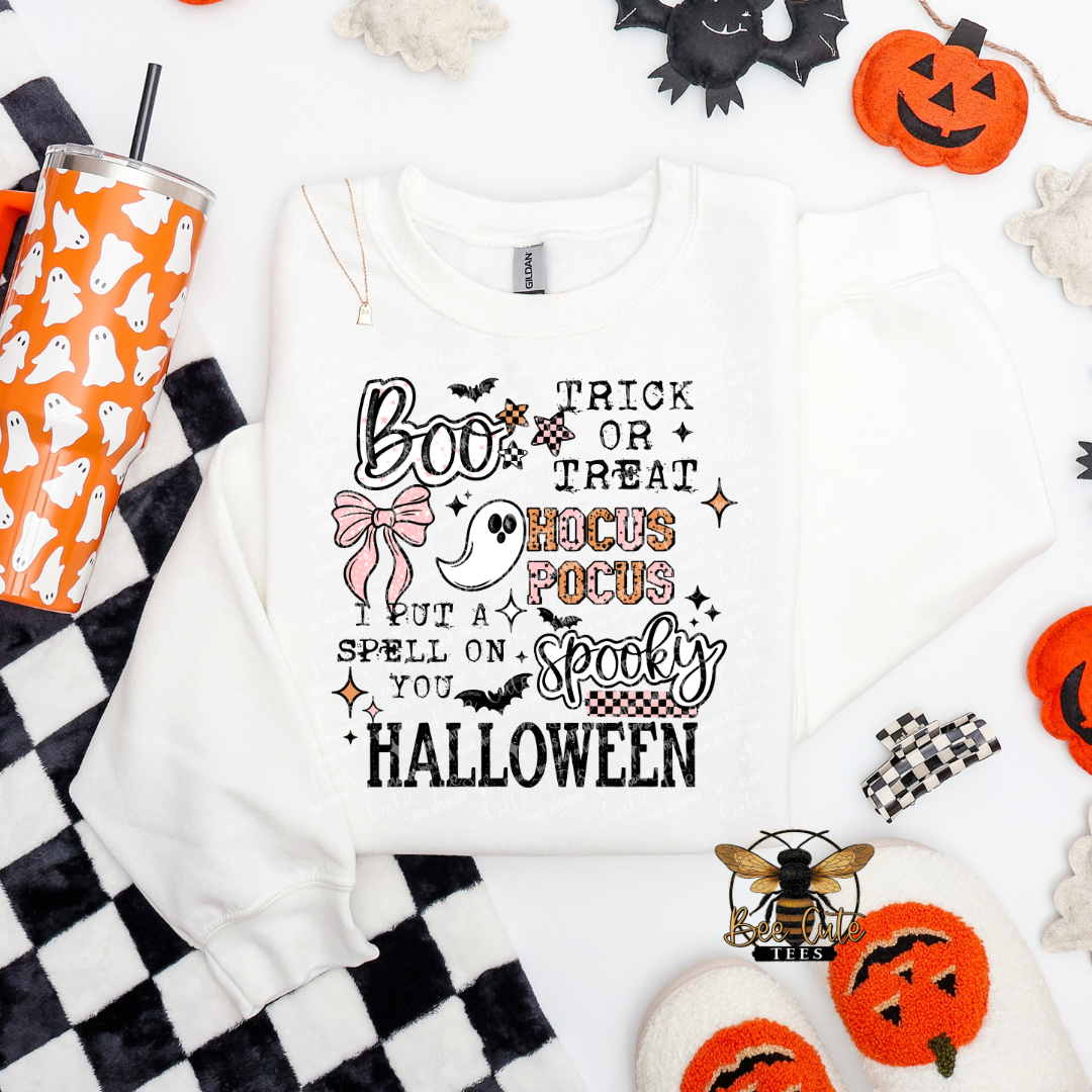 White sweatshirt with Halloween-themed text and graphics on a checkered background with Halloween decor.