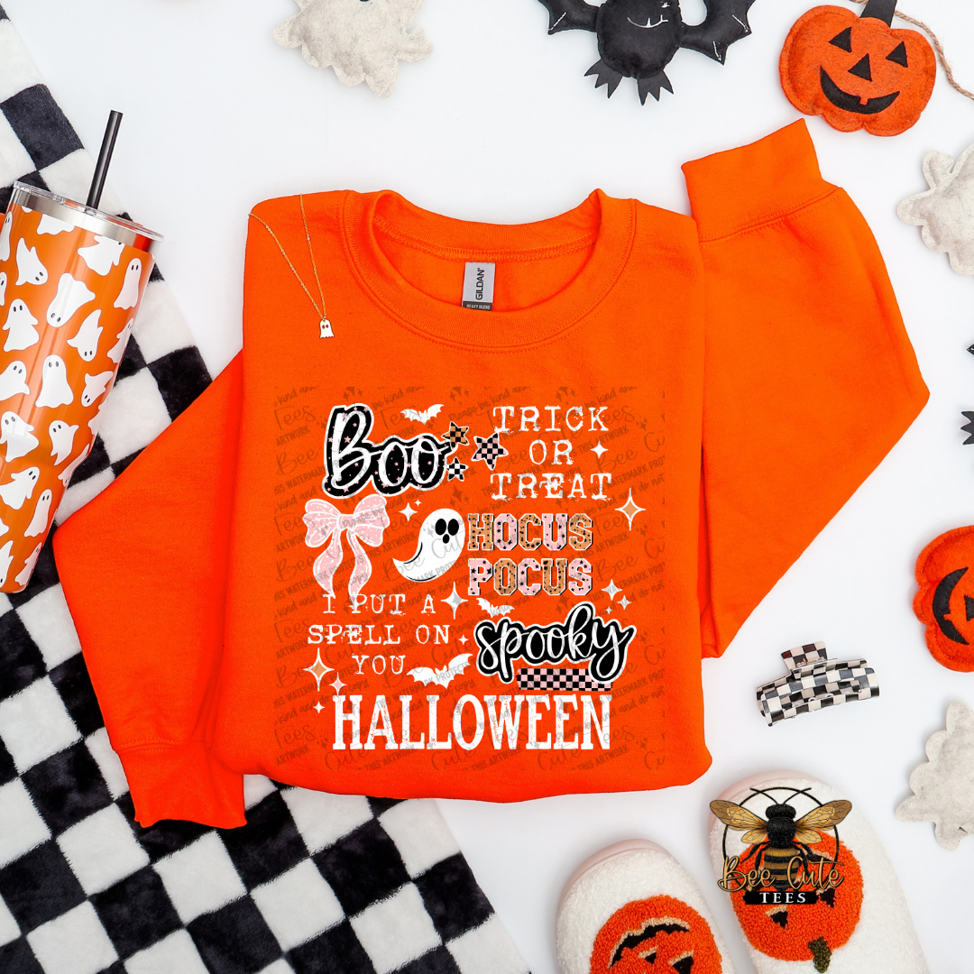 Orange sweatshirt with Halloween-themed text and graphics on a checkered background with Halloween decorations.