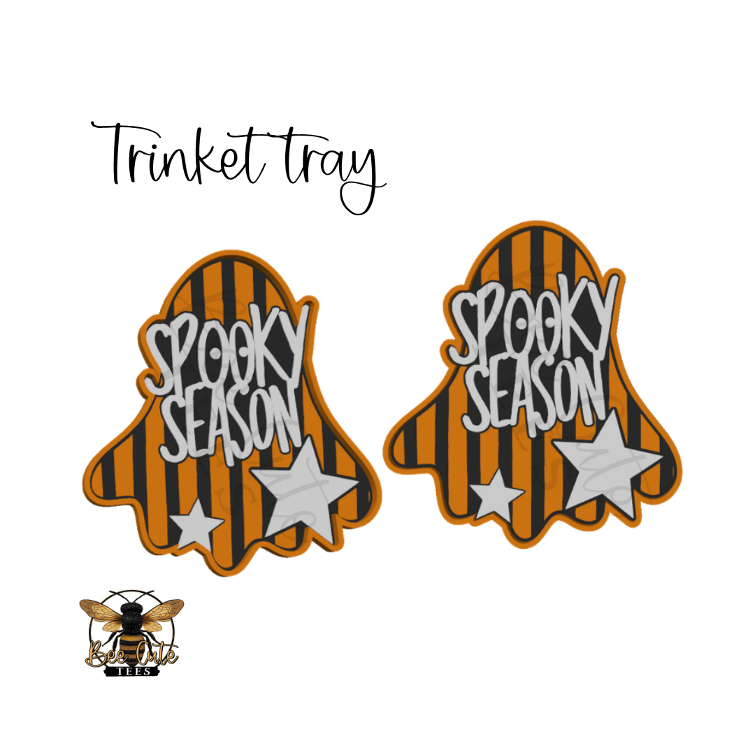 Two ghost-shaped embroidered patches with orange and black stripes and the words 'Spooky Season' in white, shown on a white background with the text 'Trinket tray' above and a bee logo below.