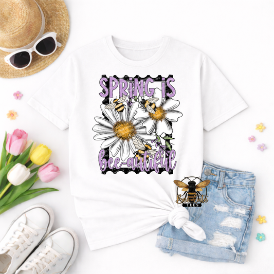 White t-shirt with 'Spring is bee-autiful' design, sunglasses, tulips, and denim shorts on a white background