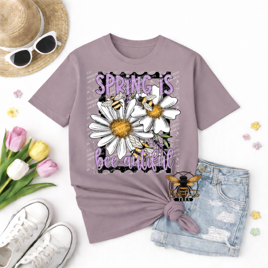 Purple t-shirt with floral and bee design, sunglasses, tulips, and denim shorts on a white background