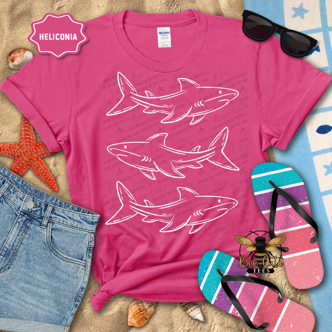 Pink t-shirt with shark designs on a beach-themed background