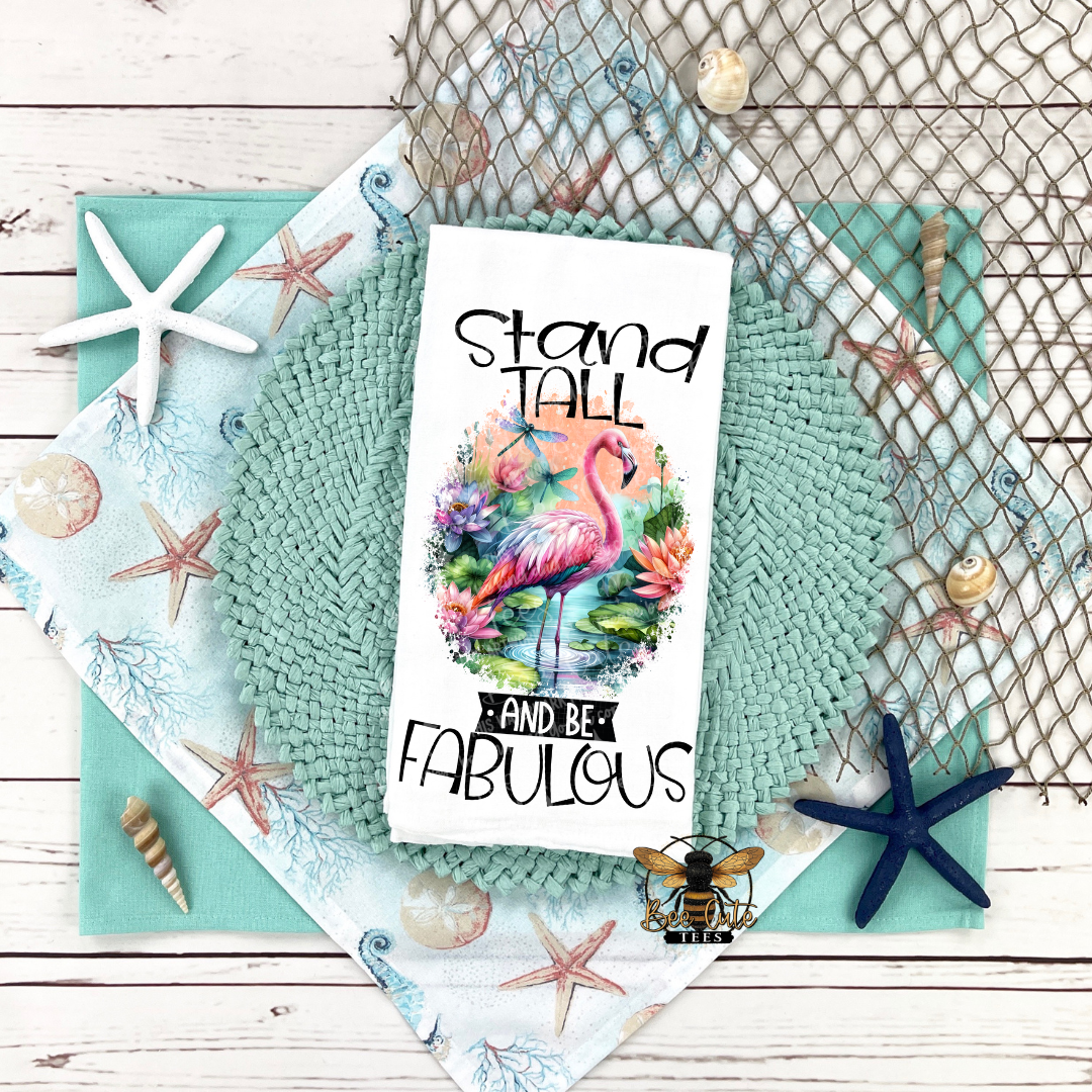 Tea towel with flamingo design and motivational quote on a textured surface with decorative elements.