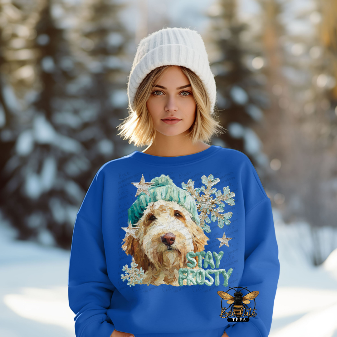 Person wearing a blue sweater with a dog graphic and 'Stay Frosty' text in a snowy landscape.