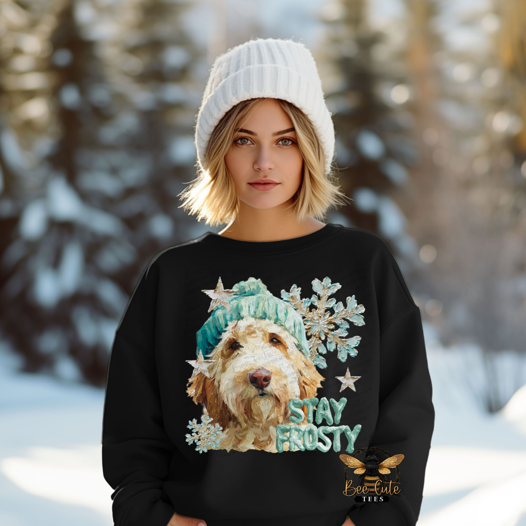 Woman wearing a black sweatshirt with a dog graphic and 'Stay Frosty' text in a snowy forest setting.