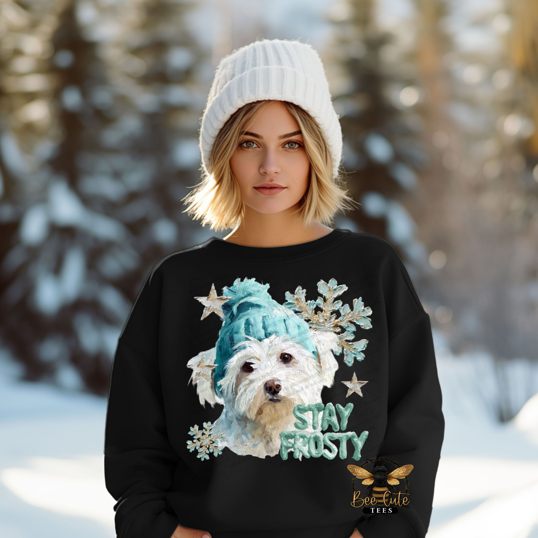 Person wearing a black sweater with a dog graphic and 'Stay Frosty' text in a snowy landscape.