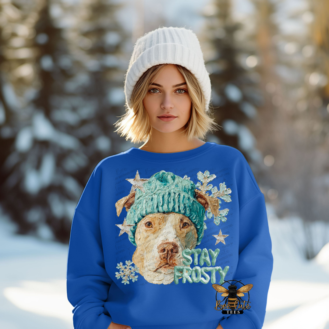 Person wearing a blue sweater with a dog graphic and 'Stay Frosty' text in a snowy landscape.