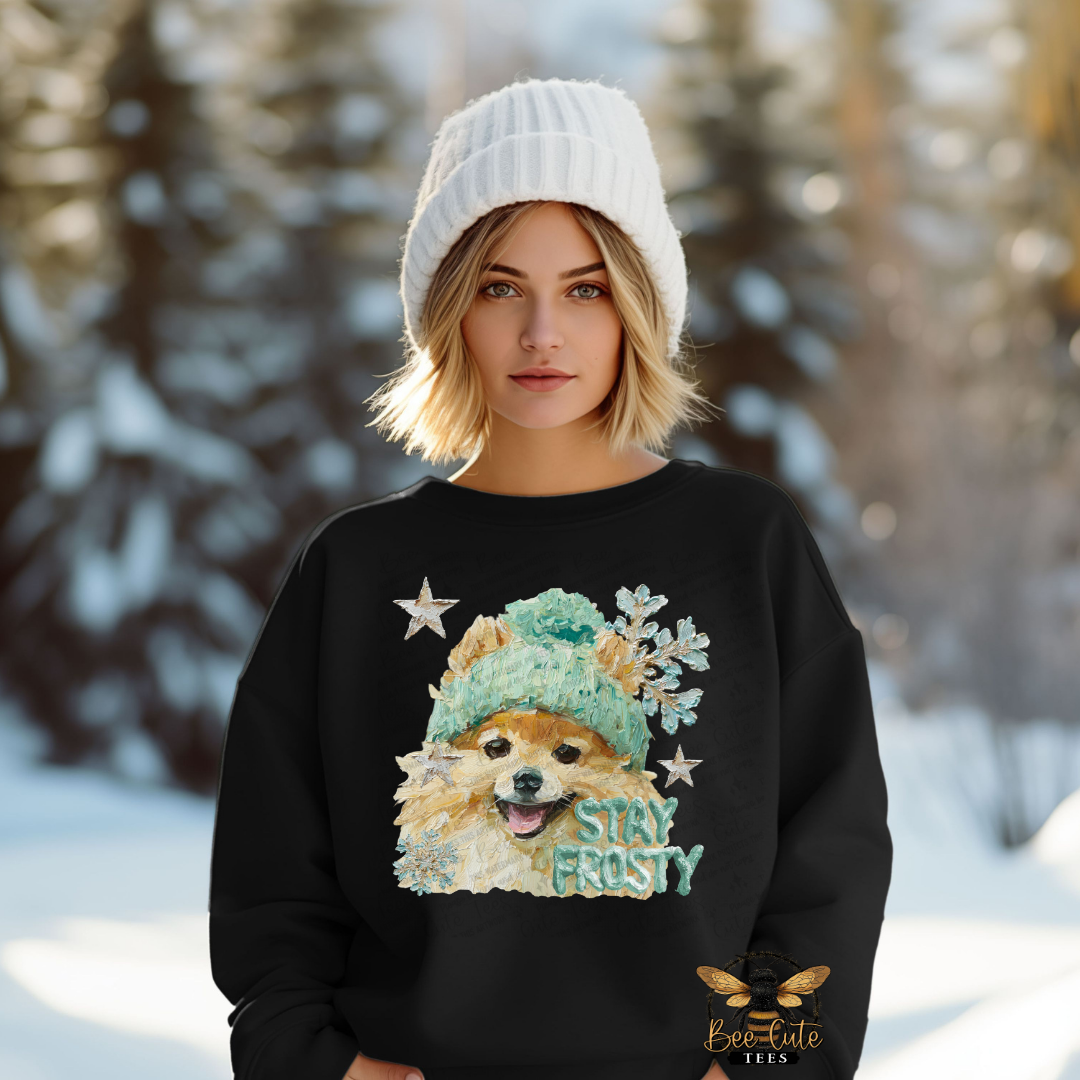 Person wearing a black sweatshirt with a dog graphic and 'Stay Frosty' text in a snowy landscape.