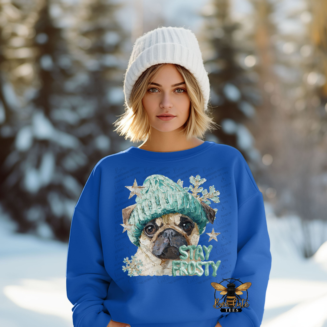 Woman wearing a blue sweater with a dog graphic and 'Stay Frosty' text in a snowy landscape.