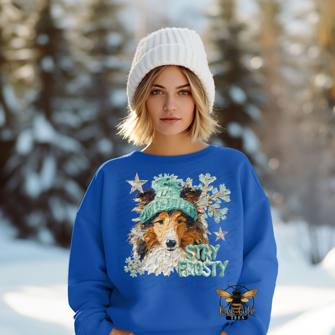 Person wearing a blue sweater with a dog design and 'Stay Frosty' text in a snowy landscape.