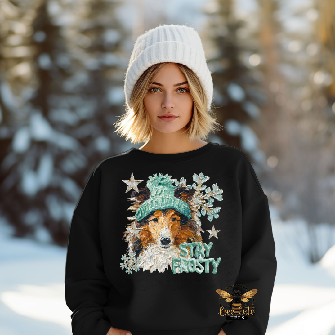 Person wearing a black sweater with a dog graphic and 'Stay Frosty' text in a snowy forest setting.