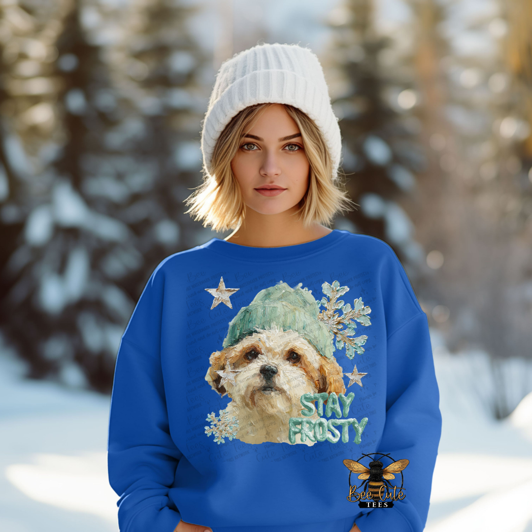 Person wearing a blue sweater with a dog graphic and 'Stay Frosty' text in a snowy landscape.