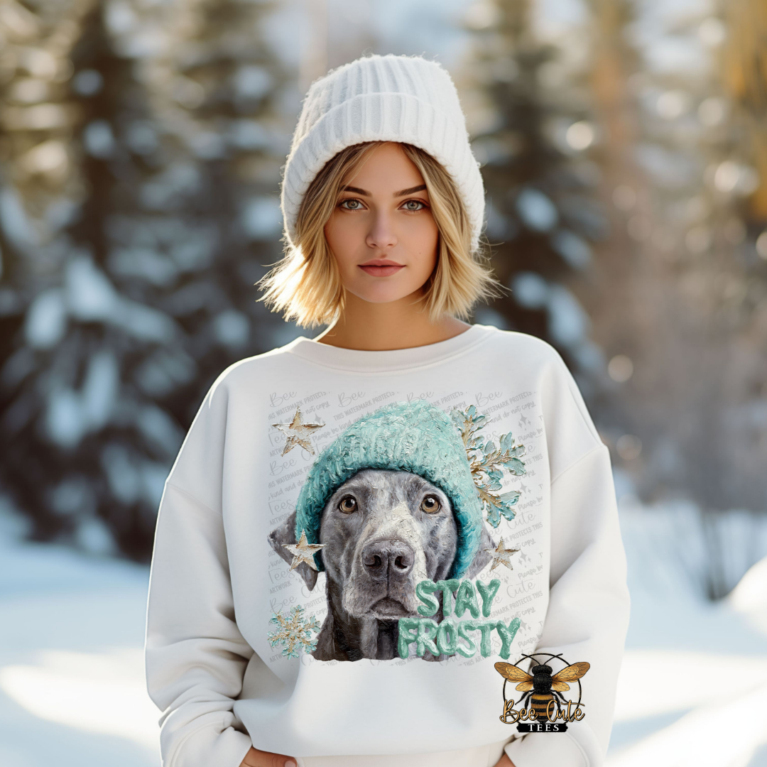 Woman wearing a sweater with a dog graphic and 'Stay Frosty' text in a snowy landscape
