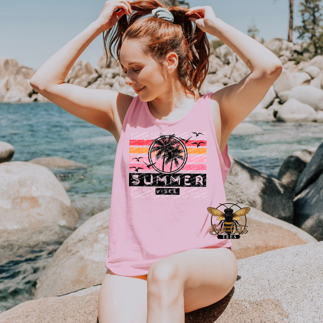 Woman wearing a pink tank top with 'Summer Vibe' design by a body of water.
