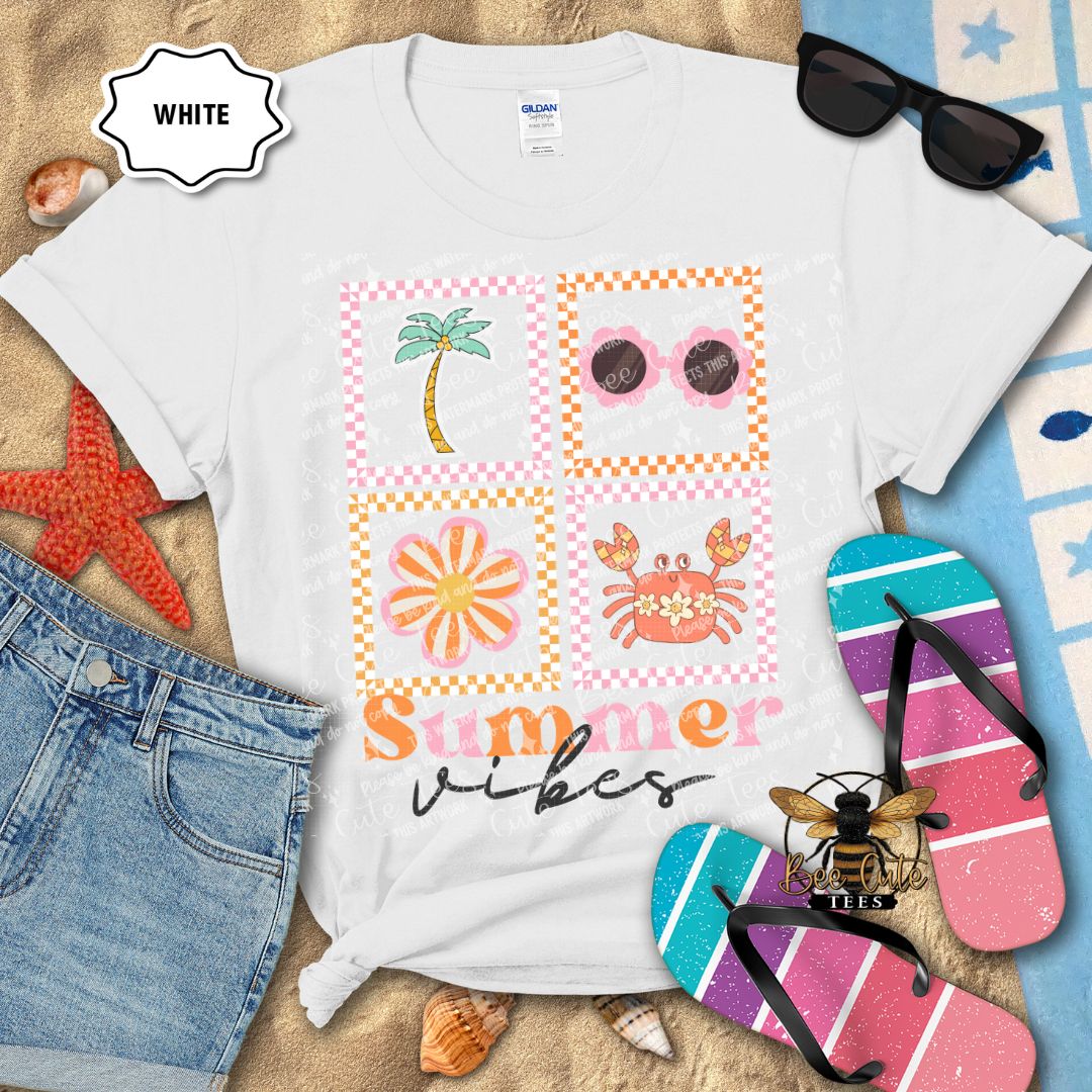 White t-shirt with summer-themed graphics and text, surrounded by beach accessories on a sandy background.