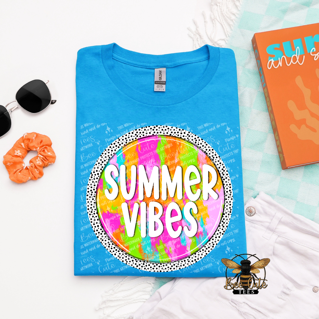 Blue t-shirt with 'Summer Vibes' design on a white surface with accessories.