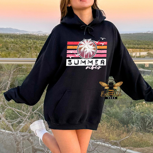 Person wearing a black hoodie with 'Summer Vibes' design outdoors.