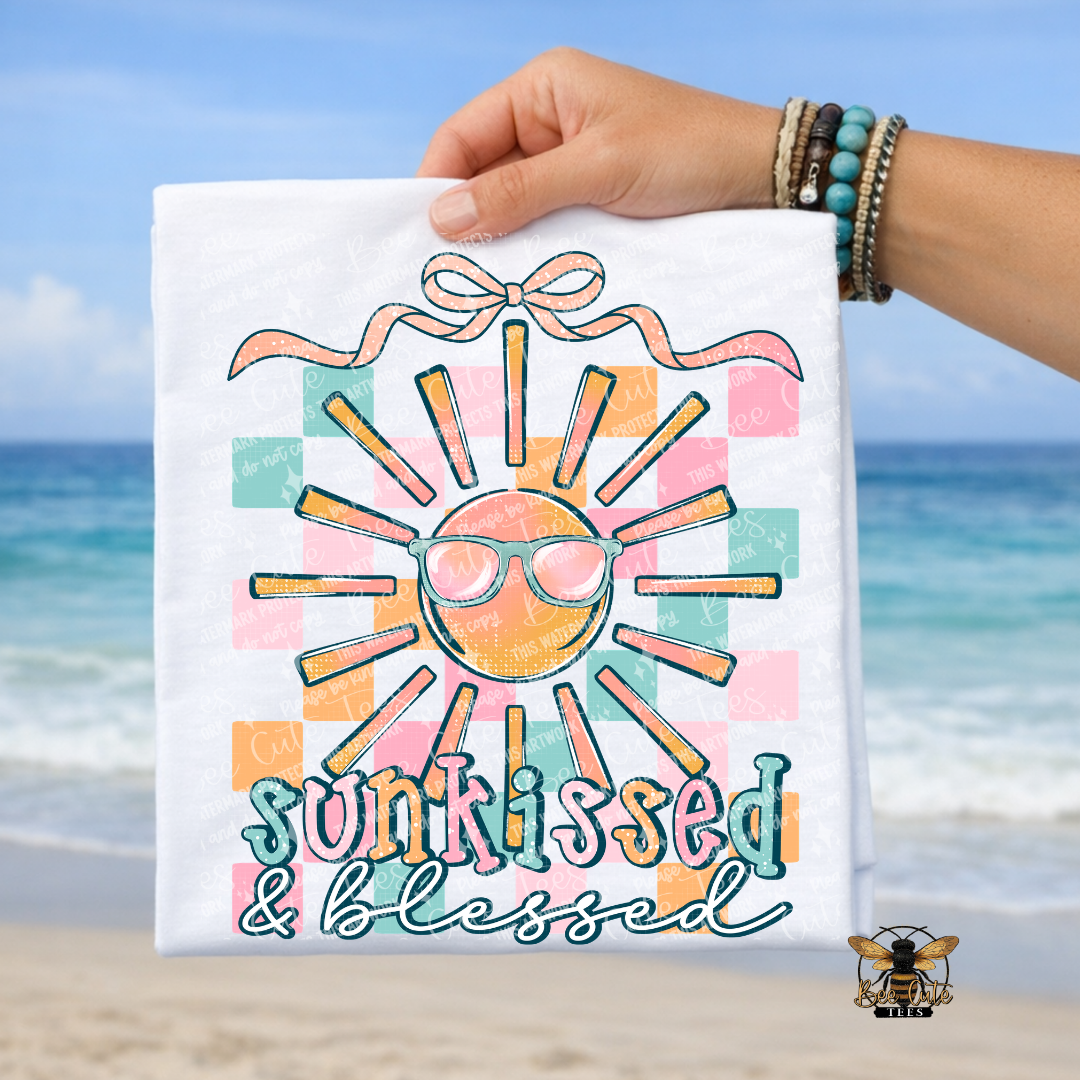 Hand holding a towel with a sun design and 'sunkissed & blessed' text against a beach background
