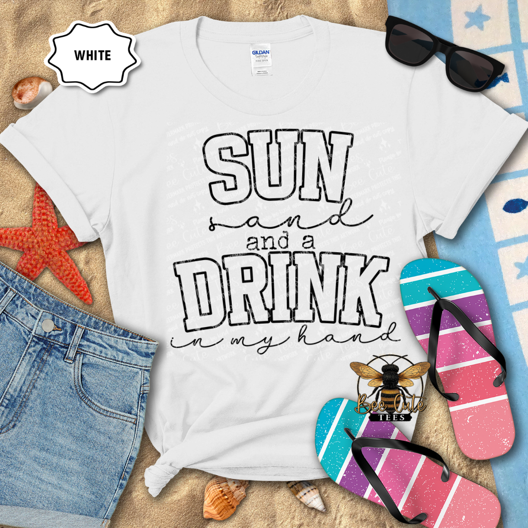 White t-shirt with 'Sun and a Drink in my hand' text and beach-themed design on a sandy background.