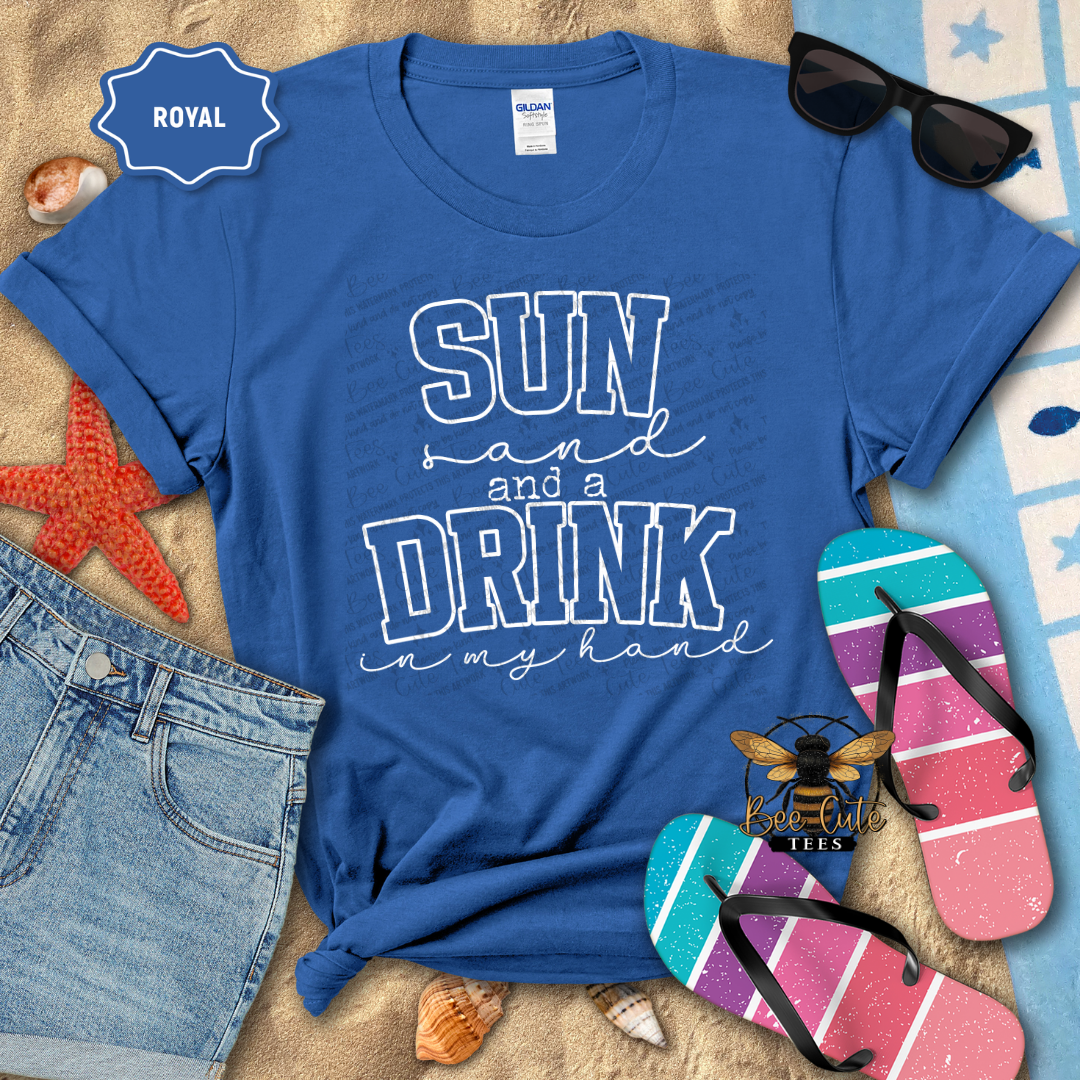 Blue t-shirt with 'Sun and a Drink in my Hand' text, sunglasses, flip-flops, and denim shorts on a beach-themed background.