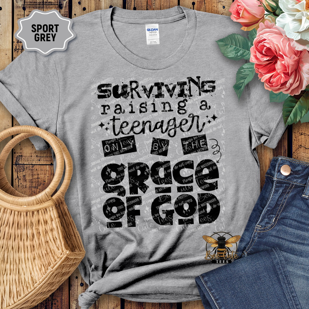 Gray t-shirt with humorous text design on a wooden surface with flowers and jeans.