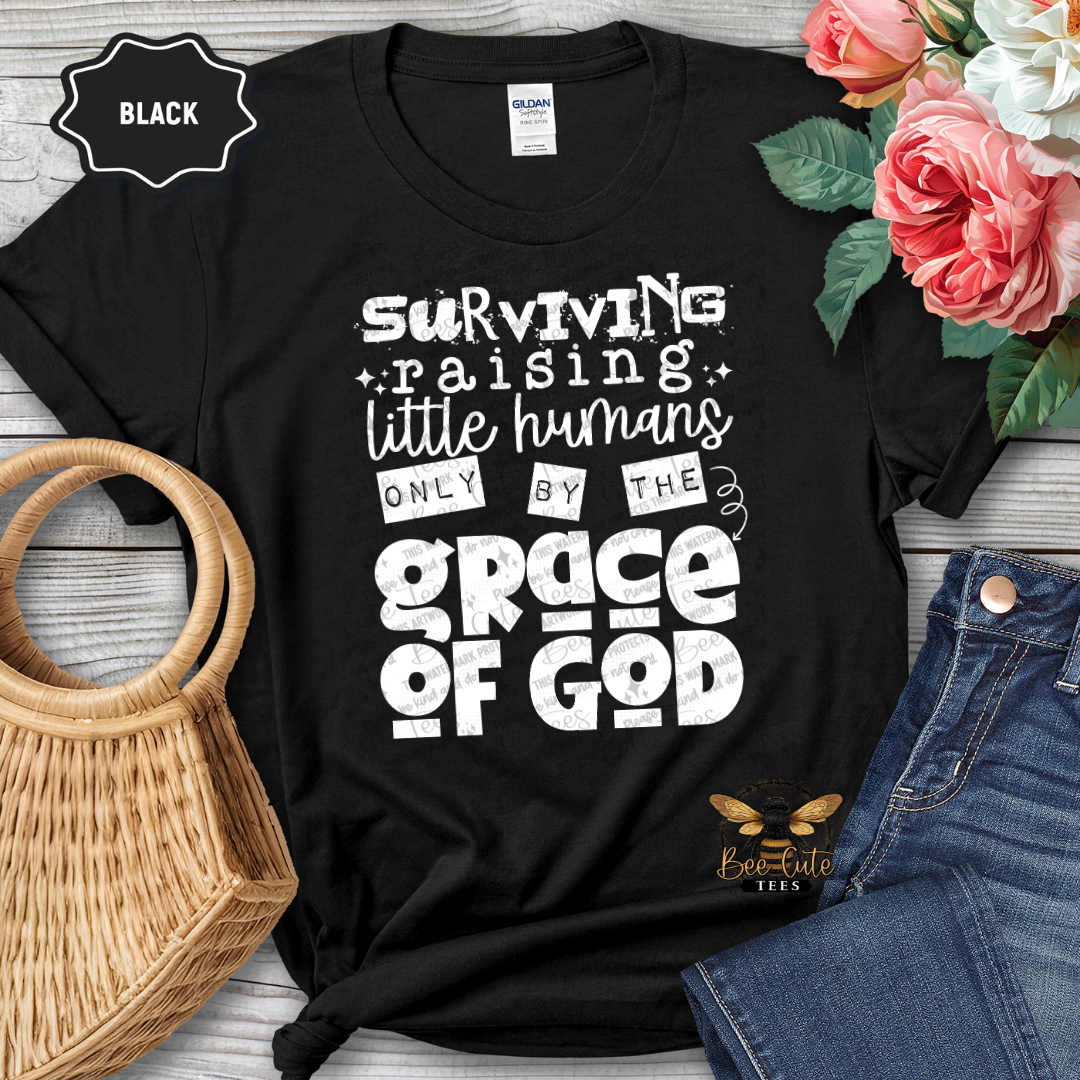 Black t-shirt with humorous text design on a wooden surface with flowers and jeans.