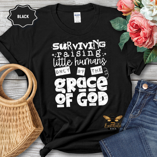 Black t-shirt with humorous text design on a wooden surface with flowers and jeans.