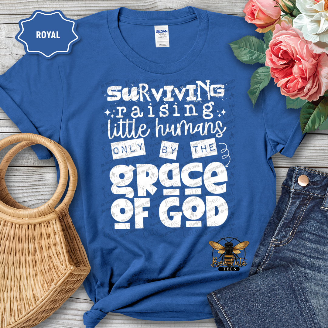 Blue t-shirt with humorous text design, placed on a wooden surface with flowers and accessories.