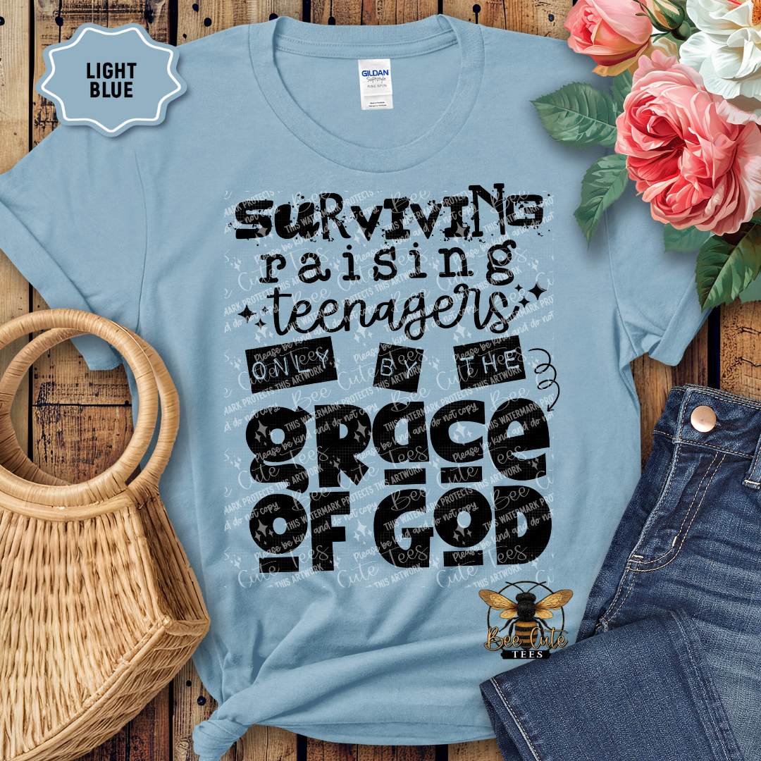 Light blue t-shirt with text design on a wooden surface with flowers and jeans.