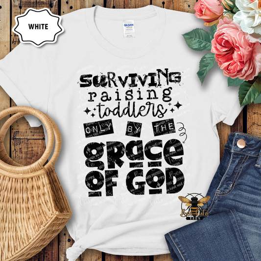 White t-shirt with humorous text design on a wooden surface with flowers and jeans.