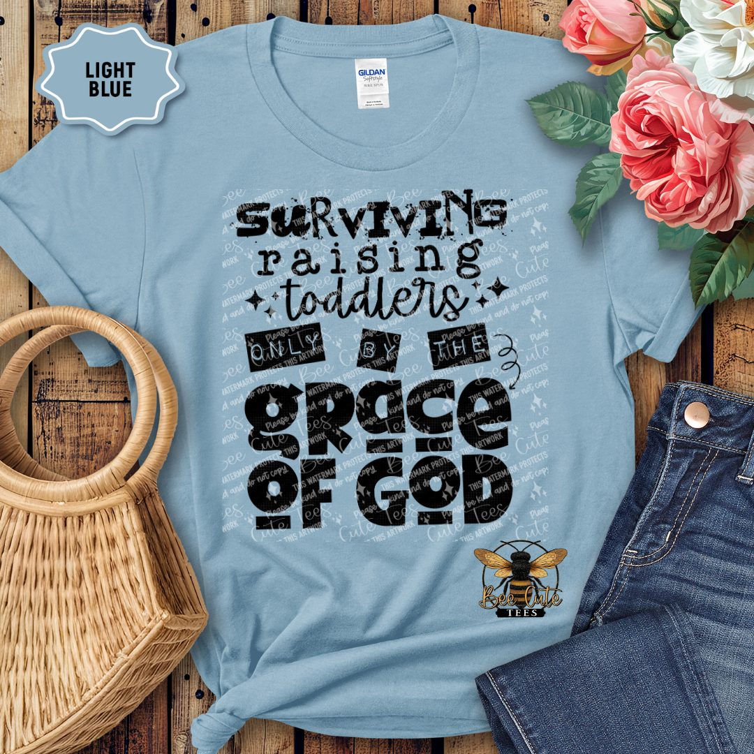Light blue t-shirt with text design on a wooden surface with flowers and jeans.